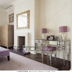 Purple lamps on mirrored glass dressing table with matching stool .
