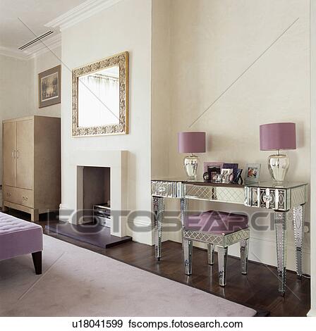 Purple lamps on mirrored glass dressing table with matching stool .